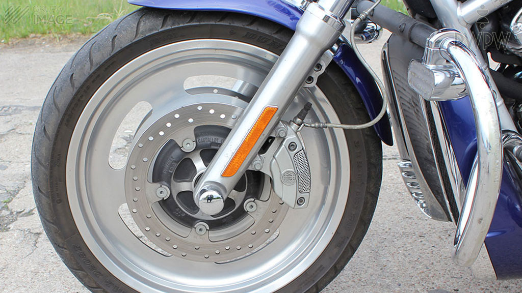 How should you respond to the side skidding of the front wheel when riding a motorcycle on a dirt road?