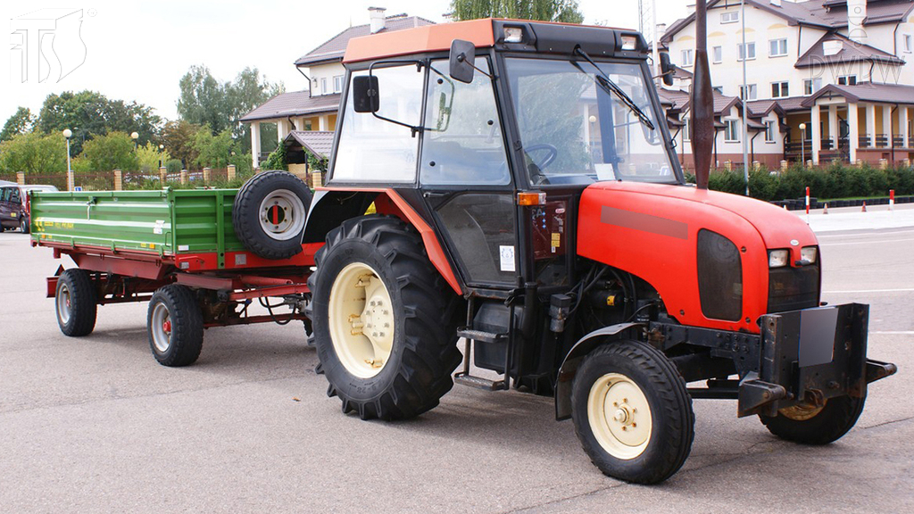 How should you observe the road behind a tractor with a trailer while reversing?